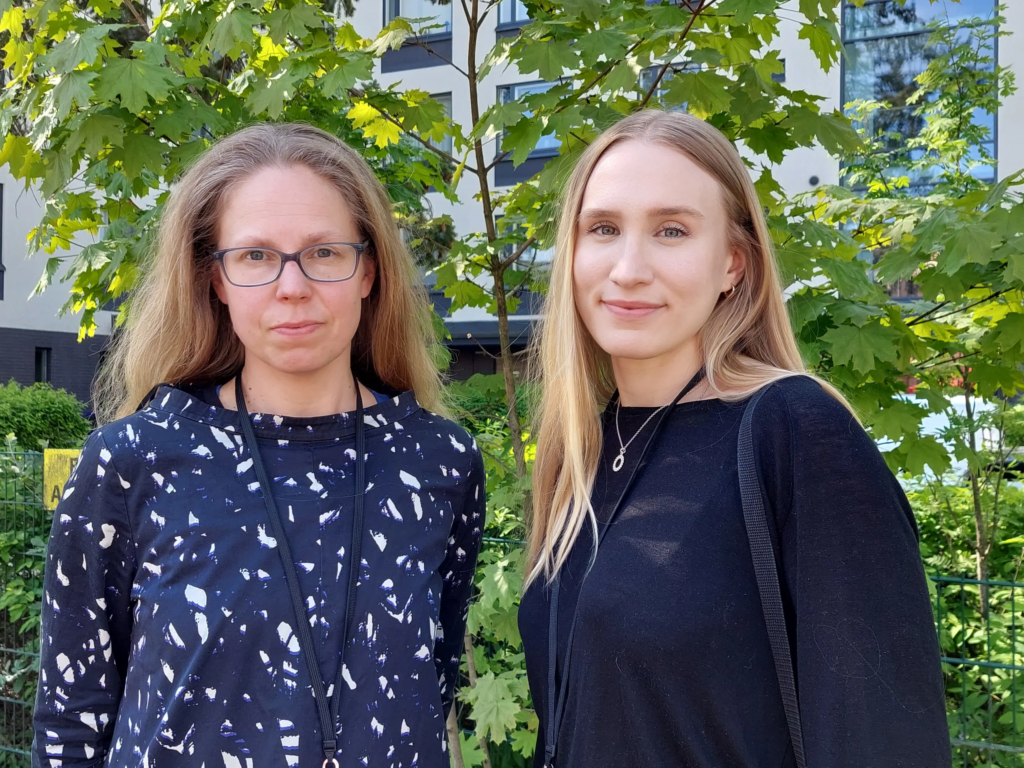 Kaksi henkilöä seisovat kasvillisuuden edessä.
