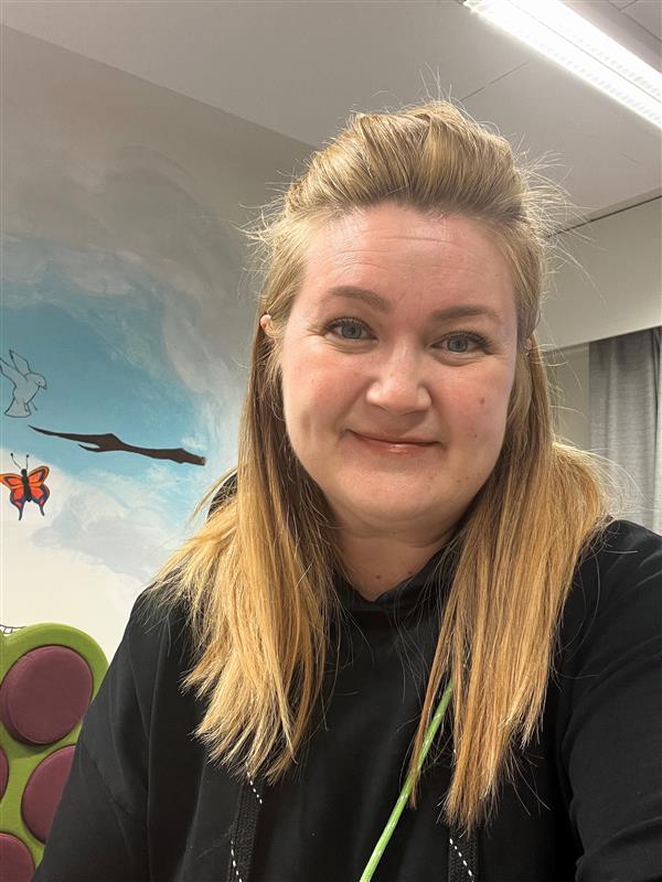 Henkilö katsoo lähikuvassa hymyillen kameraan.