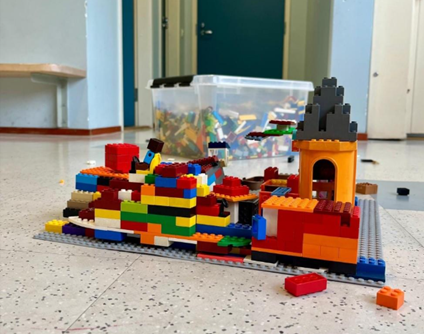 Lattialla on värikkäitä legoja, joista on tehty jonkinlainen linna.