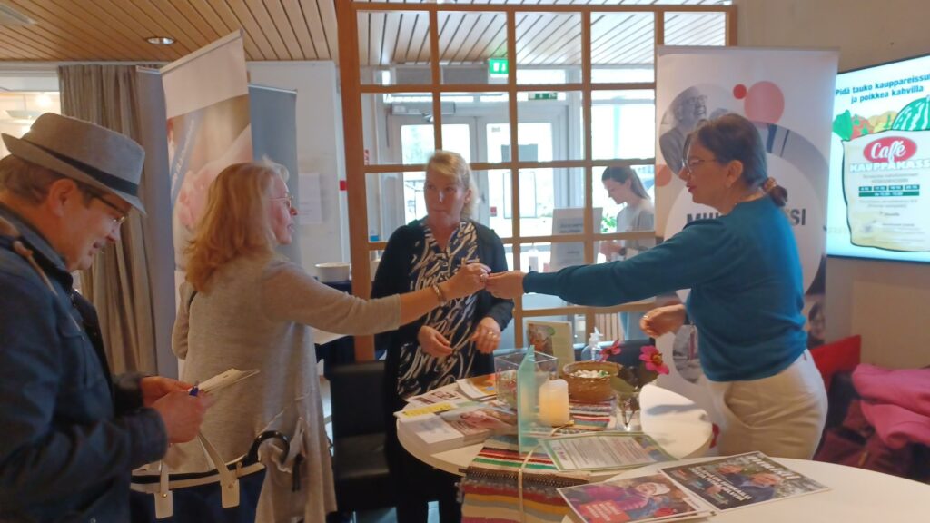 Järvenpään seurakunnan esittelypöytä Asumisen minimessuilla. Kuvassa kolme naista ja yksi mies. Pöydällä on esitteitä.