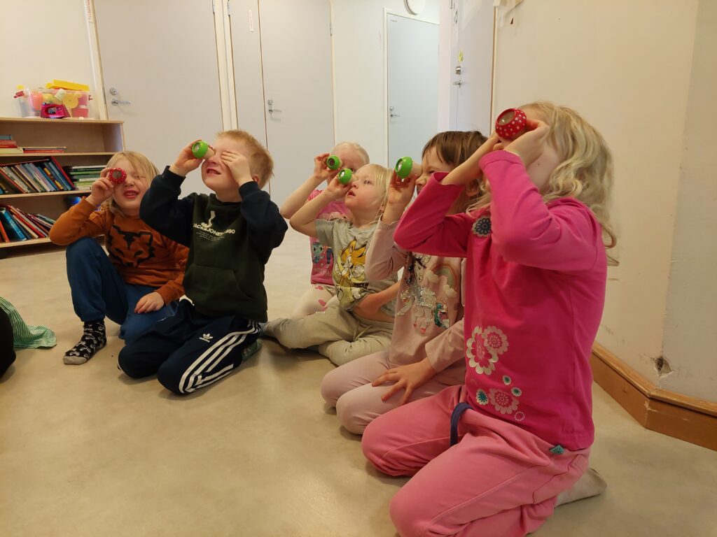 Lapset katsovat taulua suurentavien loopien läpi.