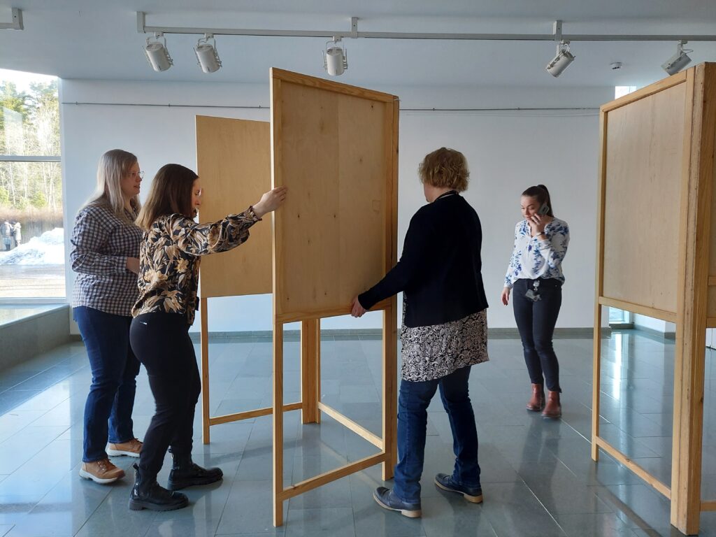 Neljä naista siirtävät vaalikoppia oikealle paikalleen Järvenpää-talolla.