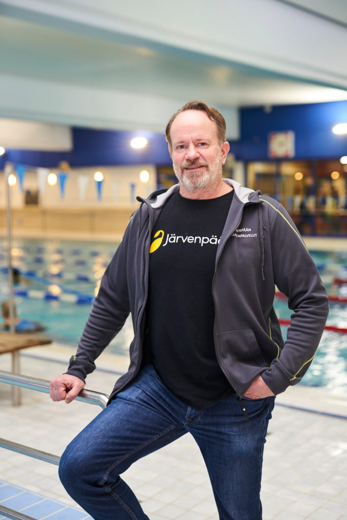 Mies seisoo kuvan etualalla uimahallissa, altaat miehen takana.