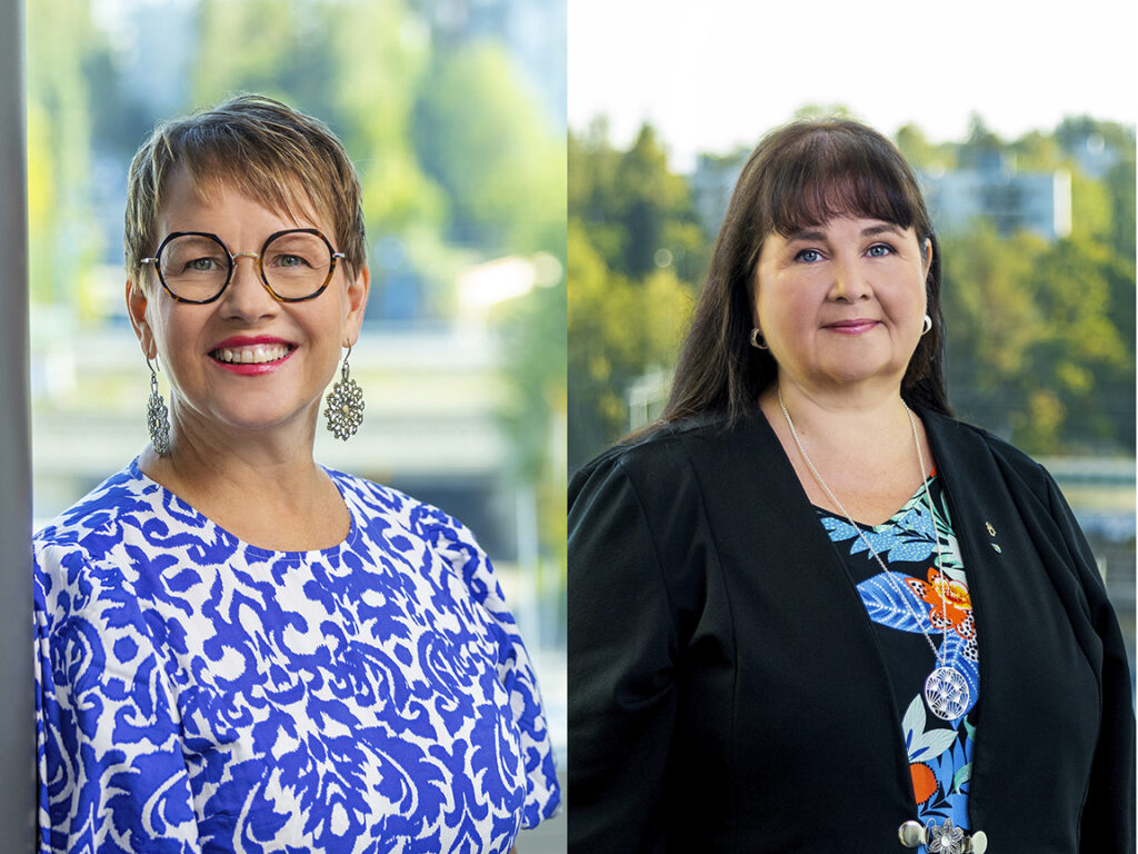 Kaksi naista kuvassa. Toisella naisella on silmälasit ja lyhyt tukka, toisella pitkä tummat hiukset.