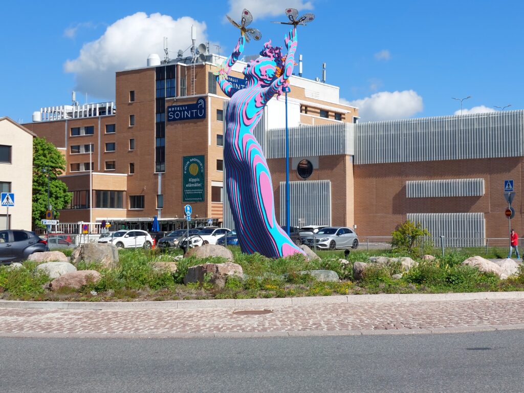 Järvenhaltija-teos liikenneympyrässä. Teoksen ympärillä on kasvamassa kukka- ja perennaistutuksia.