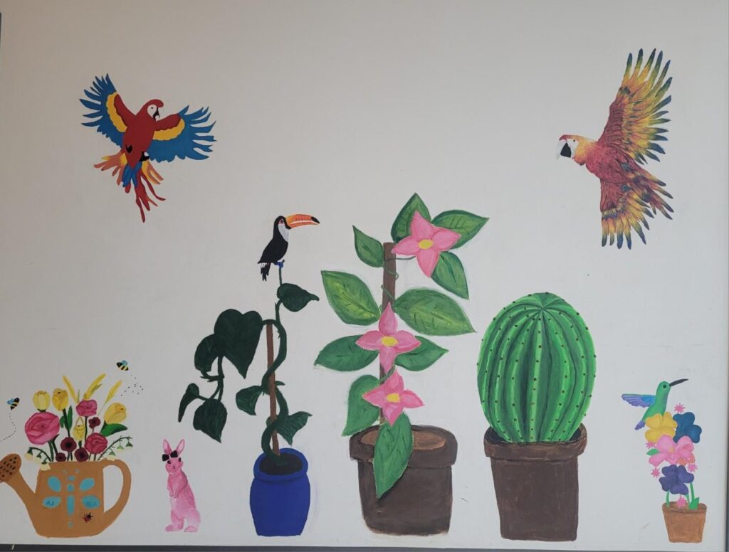 Värikkäitä lintuja ja kasveja maalattuna vaalealle seinälle.