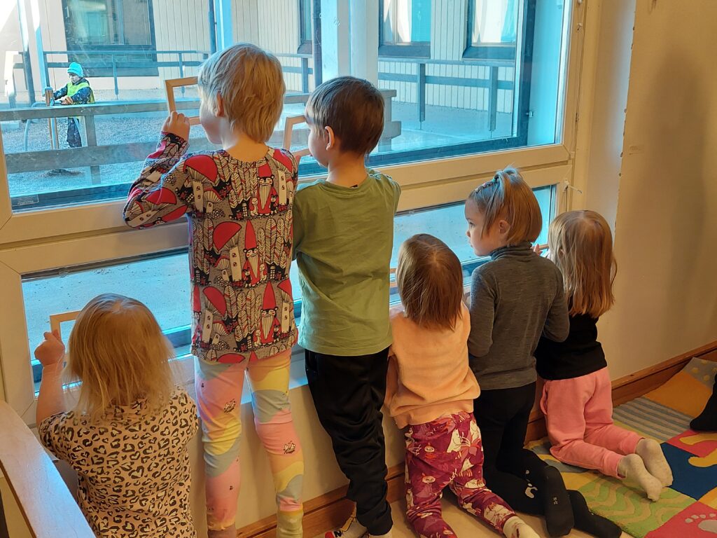 Lapset katsovat tauluraamien läpi ikkunasta ulos.