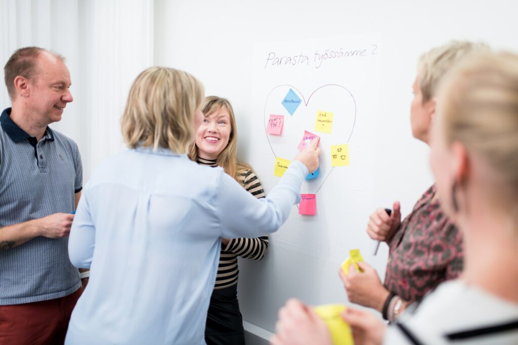 työntekijöitä kiinnittämässä post it -lappuja seinälle.